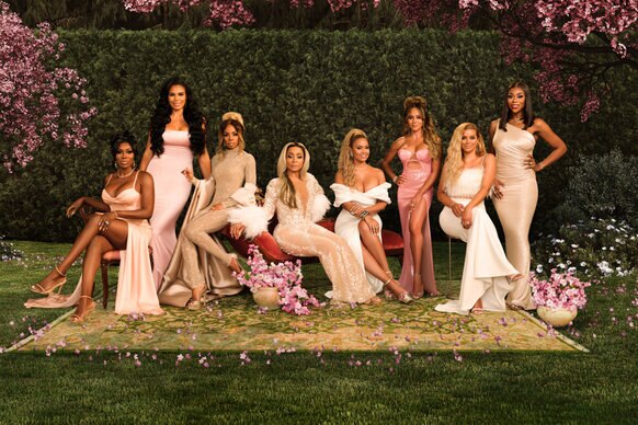 The full cast of RHOP wearing gowns in a garden of cherry blossoms.