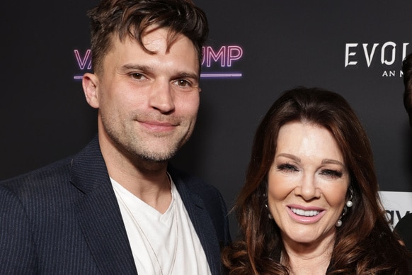 Tom Schwartz and Lisa Vanderpump smiling together in front of a step and repeat.
