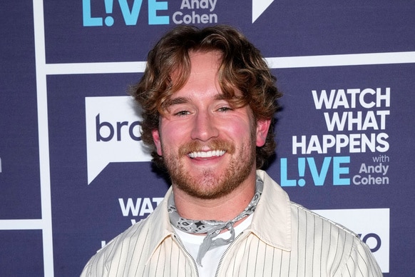 West Wilson smiling in front of a step and repeat at the Watch What Happens Live clubhouse in New York City.