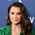 Kyle Richards posing in a green blazer in front of a step and repeat.