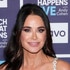 Kyle Richards smiling in front of a step and repeat at the Watch What Happens Live clubhouse in New York City.