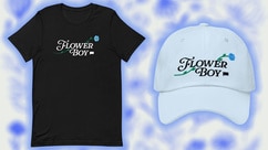 A black tee shirt and white baseball cap that say Flower Boy on them.