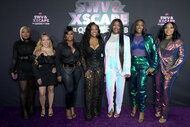 Music groups, SWV and XSCAPE posing for a photo on a red carpet.