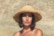 Kristina Kelly wearing a straw hat and posing in an off shoulder top.