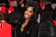 Porsha Williams smiling while sitting in a sports arena.