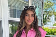 Gia in a pink romper wearing white sunglasses on her head outdoors.