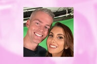 Ryan Serhant and Emilia Serhant smile together in front of a green screen.