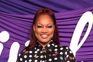 Garcelle smiling in front of a purple step and repeat.