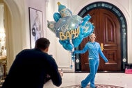 Paris Hilton holds a balloon bouquet for her son before his birth while her husband takes photos of her.