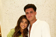 Gia Giudice and Christian Carmichael smiling and posing together in front of a tile column.