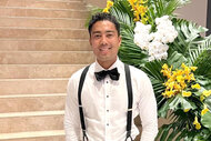 Jason Caperna wearing suspenders and a bow tie in front of a floral arrangement.