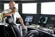 Captain Kerry Titheradge talking on his walkie talkie in the wheelhouse of the St. David yacht.