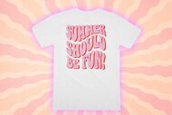 White tee shirt with the copy: Summer Should Be Fun, in front of a color orange and pink design