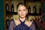 Ariana Madix wearing a sheer navy gown in front of a bar.