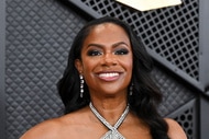 Kandi Burruss smiling in front of a step and repeat.