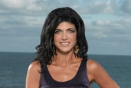 Teresa Giudice smiling in front of the Jersey Shore in a purple dress.