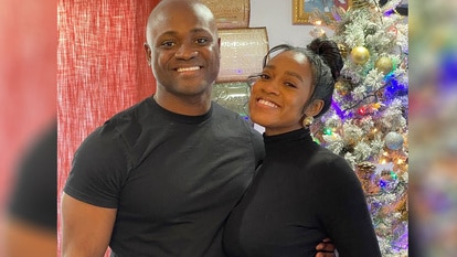 Jasmine Ellis Cooper with her husband, Silas Cooper, celebrate Christmas together in front of a Christmas tree.