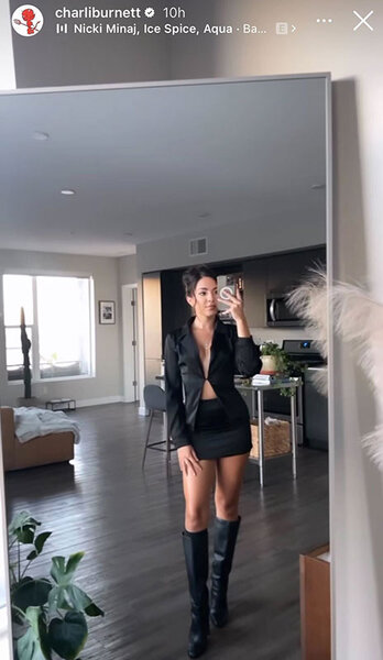 Charli takes a mirror selfie of her all black outfit including a mini skirt and knee high boots.