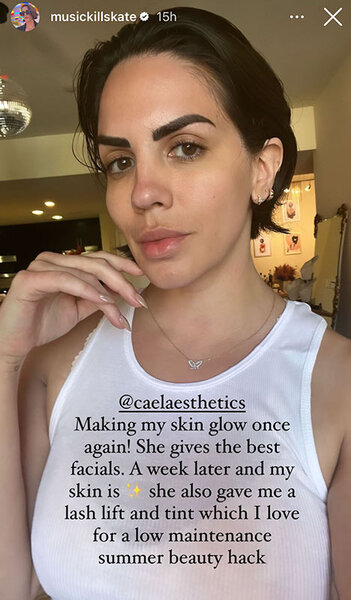 Katie Maloney takes a selfie with slicked back hair wearing a white tank top.