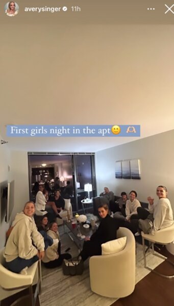 Avery Singer's guests sitting in her new Chicago, Illinois living room. Overlaid text: "First girls night in the apt [Slightly Smiling Face emoji] [Heart Hands emoji]".