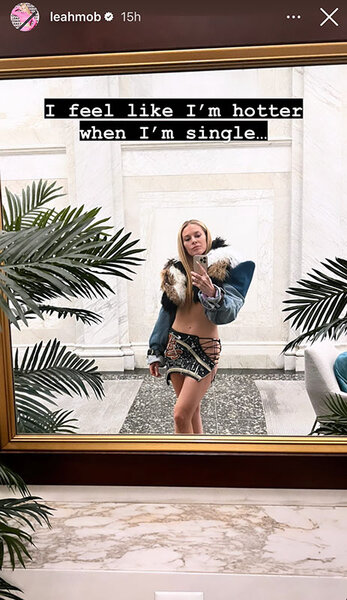 Leah McSweeney poses for a mirror selfie in a denim jacket with fur trim and a crystal embellished mini skirt. Overlaid text, "I feel like I'm hotter when I'm single."