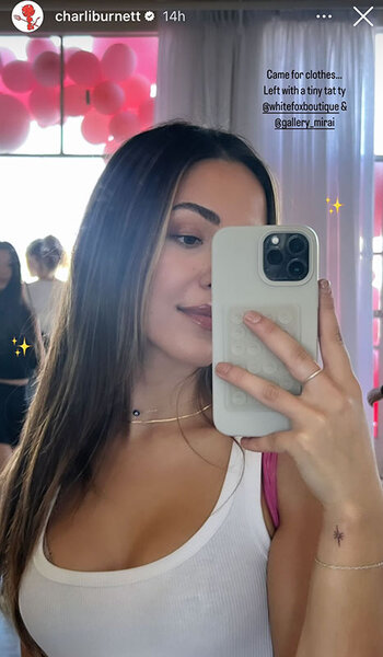 Charli Burnett shows her new sparkle tattoo while posing in a mirror for a selfie.