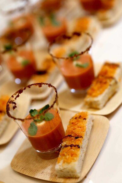Shot glasses of tomato soup with garnishment and bread at BravoCon 2023