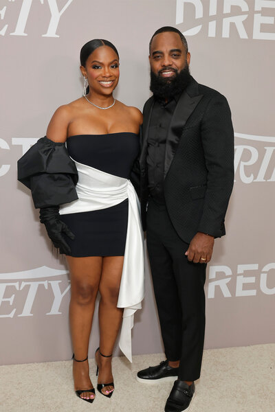 (L-R) Kandi Burruss, in a black and white dress, and Todd Tucker, in all black, pose together.