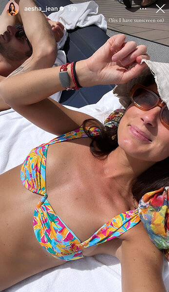 Aesha Scott wearing a hat and sunglasses in a colorful bikini.