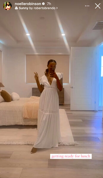 Noelle Robinson in front of a mirror wearing a white dress in her bedroom.