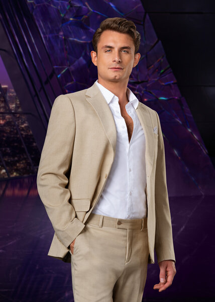 James Kennedy wearing a beige suit while in a purple room overlooking LA.