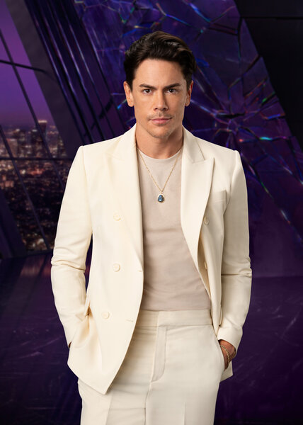 Tom Sandoval wearing a white suit while in a purple room overlooking LA.