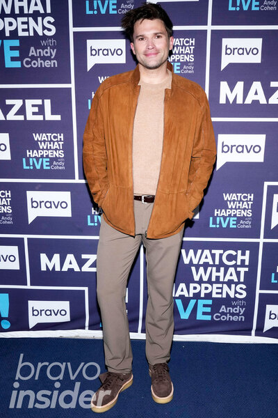 Tom Schwartz wearing an earth-toned outfit in front of a step and repeat at the Watch What Happens Live clubhouse in New York City.