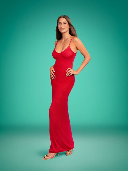 Full length of Amanda Batula wearing a red floor length dress in front of a green backdrop