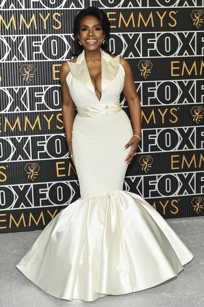 Sheryl Lee Ralph smiling on the Emmys step and repeat wearing a white, fitted, gown.