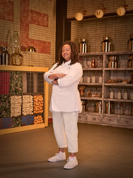 Full length of Amanda Turner in her chef's uniform in a kitchen pantry.