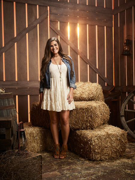 Brittany Cartwright wearing a white dress and denim jacket in a barn