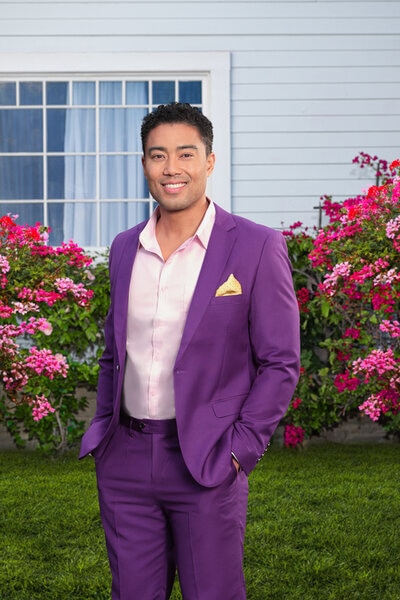 Jason Caperna wearing a purple suit on a grass lawn.