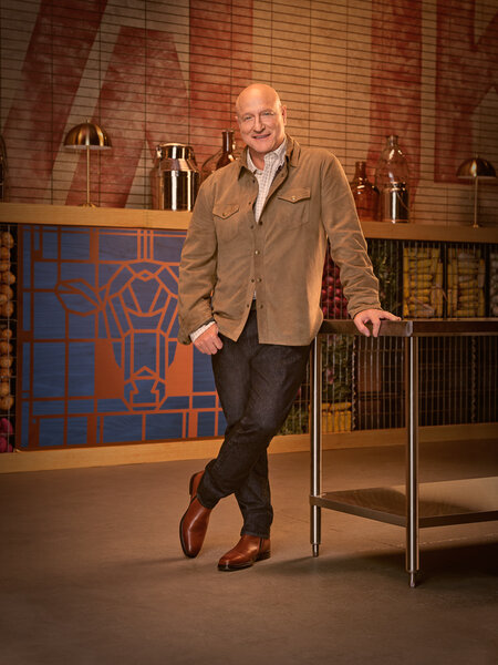 Full length of Tom Colicchio wearing a brown shirt and jeans in a kitchen pantry