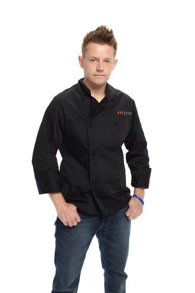Richard Blais wearing his chef's jacket and jeans in front of a white back drop