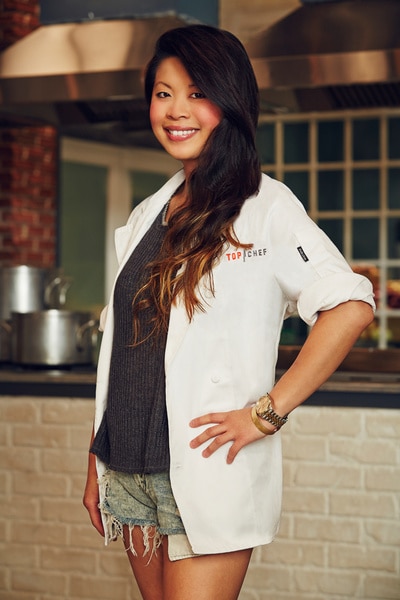Mei Lin wearing her chef's jacket and denim shorts in a kitchen.