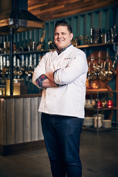 Joseph Flamm wearing his chef's jacket in the Top Chef kitchen.