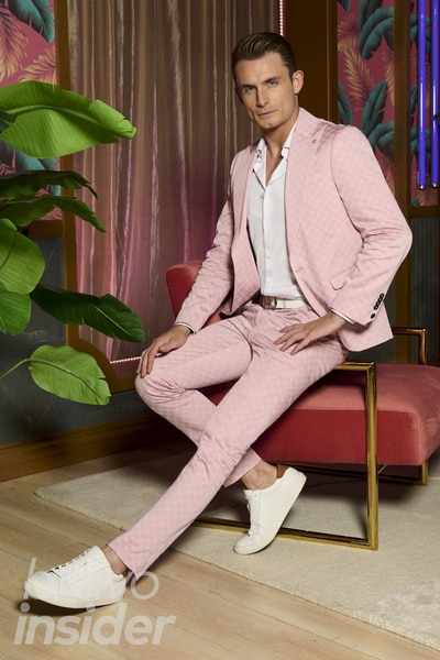 James Kennedy wearing a pink blazer in front of a champagne curtain.