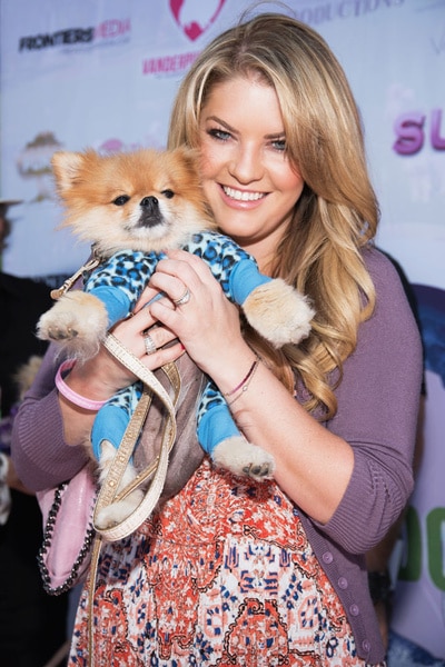 Pandora Vanderpump Sabo holding her mother's small dog at a animal event
