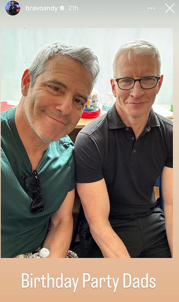 Andy Cohen and Anderson Cooper smiling together at a kids birthday party.