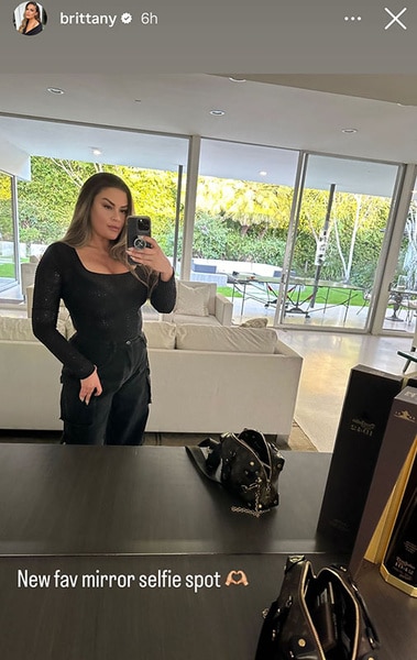 Brittany Cartwright posing in an all black outfit in a mirror.