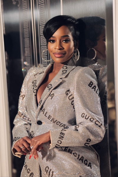 Shamea Morton Mwangi wearing a gucci suit in front of a mirrored backdrop