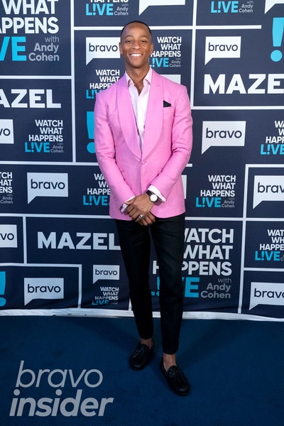 Full length of Nick Arrington wearing a pink blazer in front of the Watch What Happens step and repeat