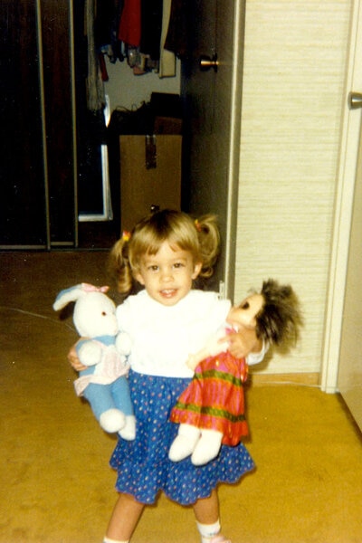 Lisa Hochstein as a child holding dolls.