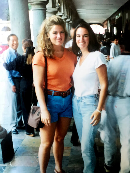 Emily wearing an orange top and denim shorts with a friend.